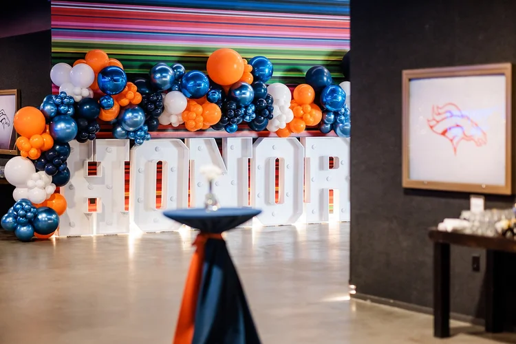 Honor marquee letters with Broncos orange navy balloon installation Mission Ballroom Denver