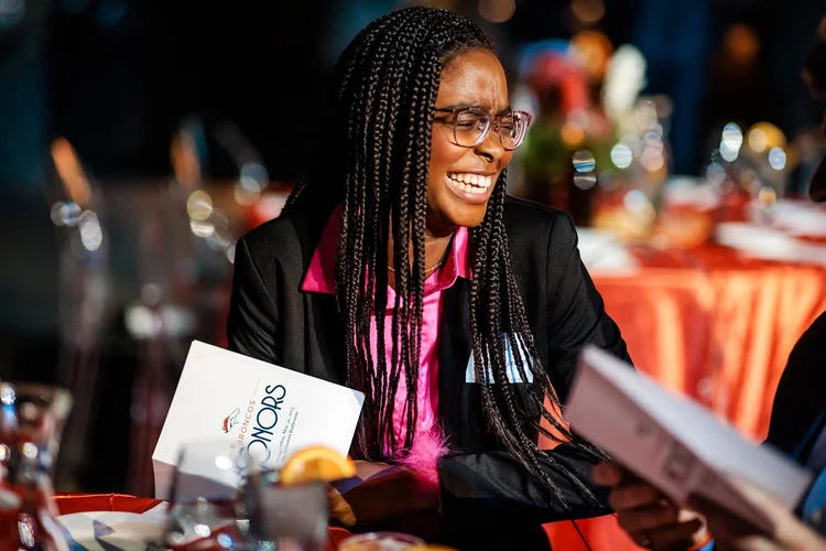 Guest smiling and holding Broncos Honors program booklet at awards event Denver Colorado