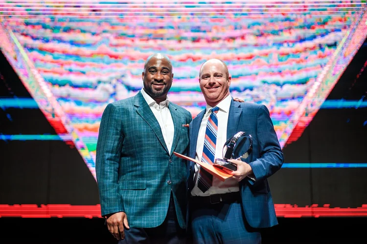 Two men posing with Broncos Honors award trophy on stage at Mission Ballroom Denver Colorado